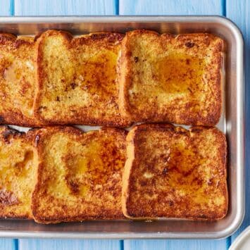 Sheet Pan French Toast with maple syrup and fresh strawberries.
