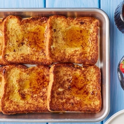 Sheet Pan French Toast with maple syrup and fresh strawberries.