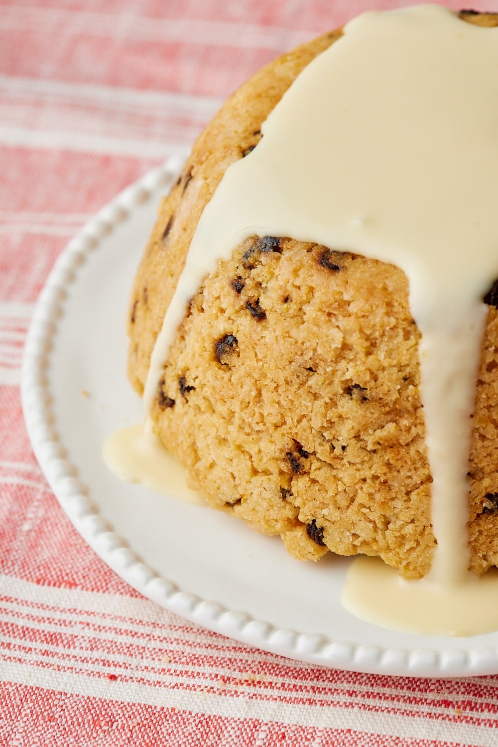 Spotted Dick11 Close-up of Spotted Dick pudding topped with custard, showing its currant-studded golden crust.