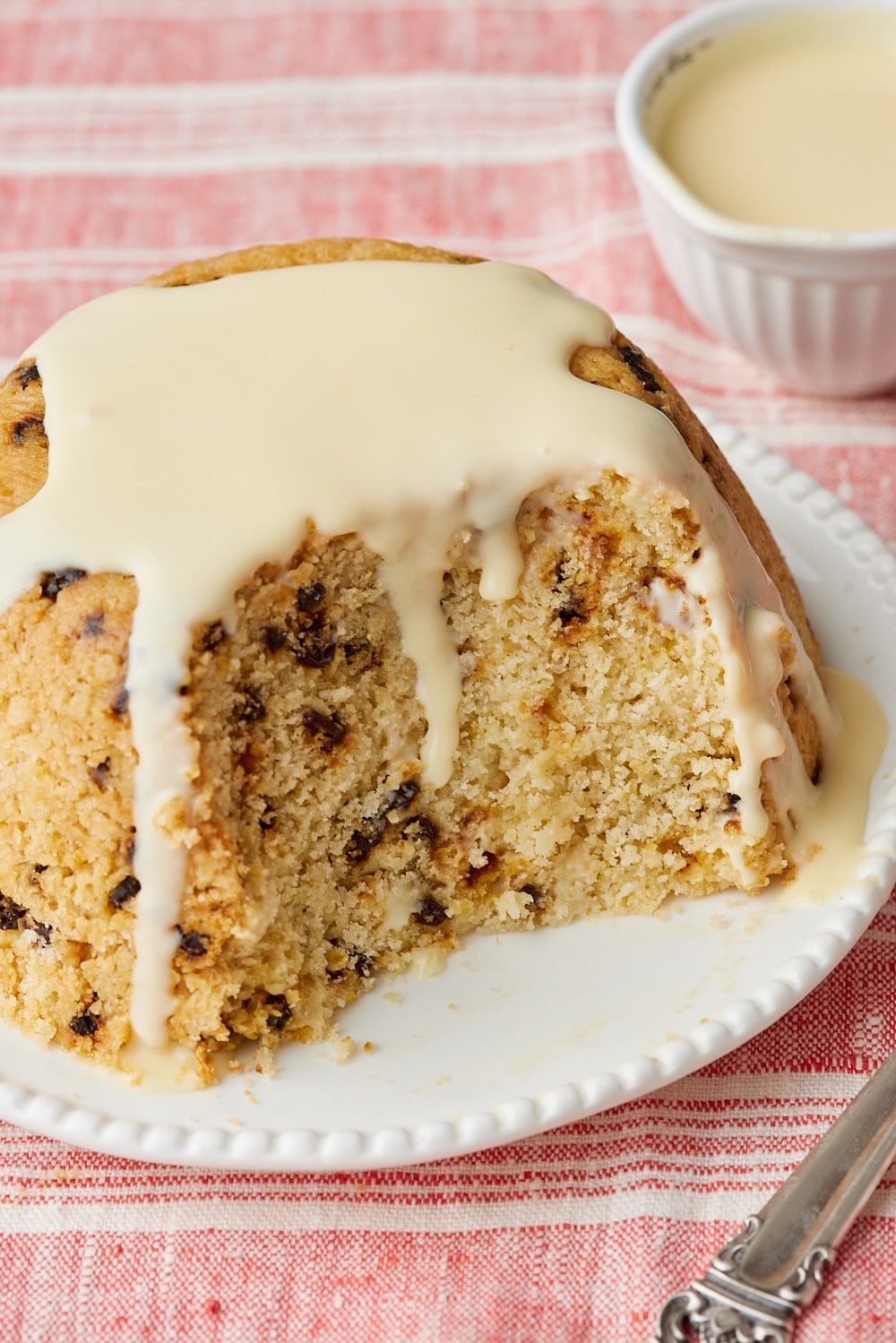 Spotted Dick13 Spotted Dick pudding sliced and topped with custard, showing the tender currant-studded interior.