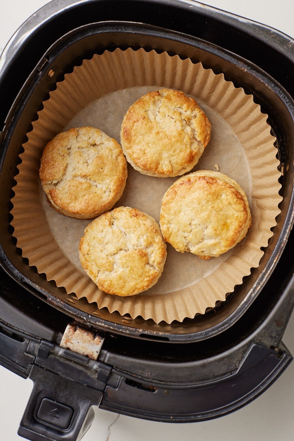Air Fryer Scones6 Four golden, flaky Air Fryer Scones baked in a parchment-lined air fryer basket, with lightly crisp tops and tender centers.