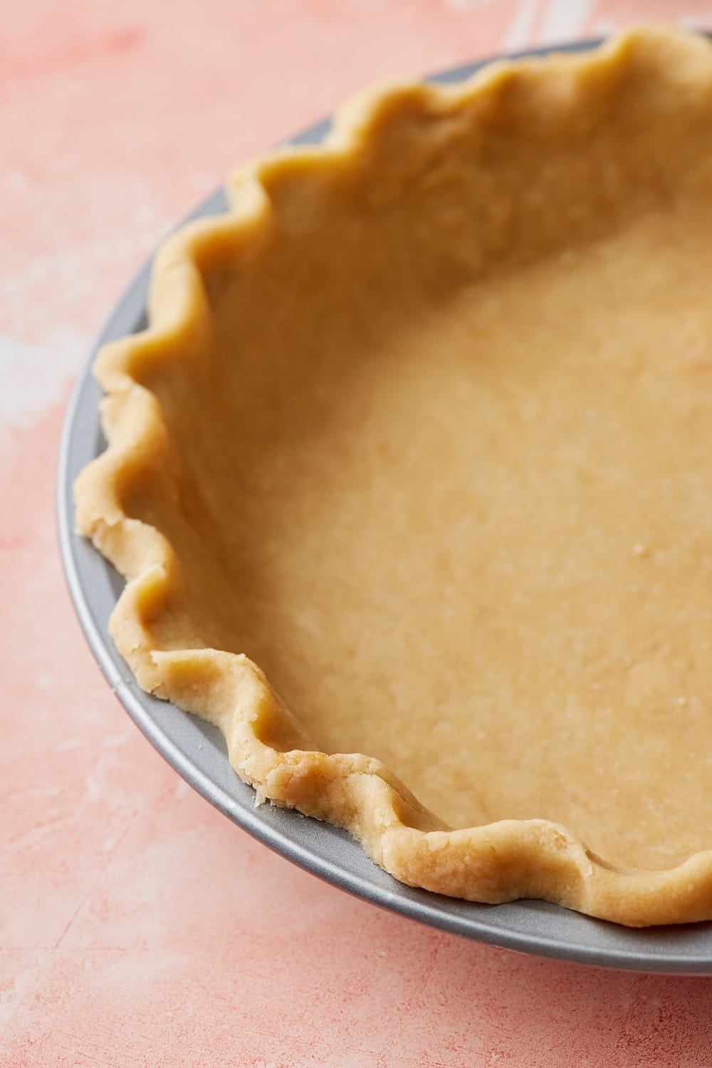 Close-up of homemade brown butter pie crust pressed into a pie pan with a decorative crimped edge, ready to be filled and baked.