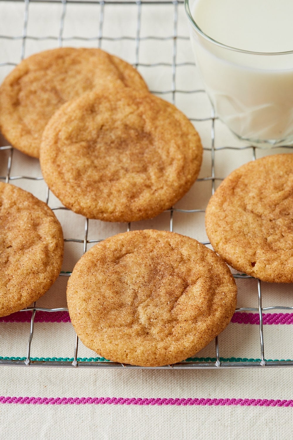 Brown Butter Snickerdoodles10 Brown butter snickerdoodle cookies coated in cinnamon sugar arranged on a wire cooling rack, with a glass of milk in the background.
