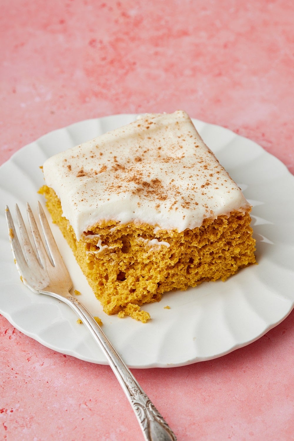 Pumpkin Spice Cake w Cake Mix7 Slice of pumpkin spice cake with a moist, golden crumb and thick cream cheese frosting sprinkled with cinnamon, served on a white plate with a fork.