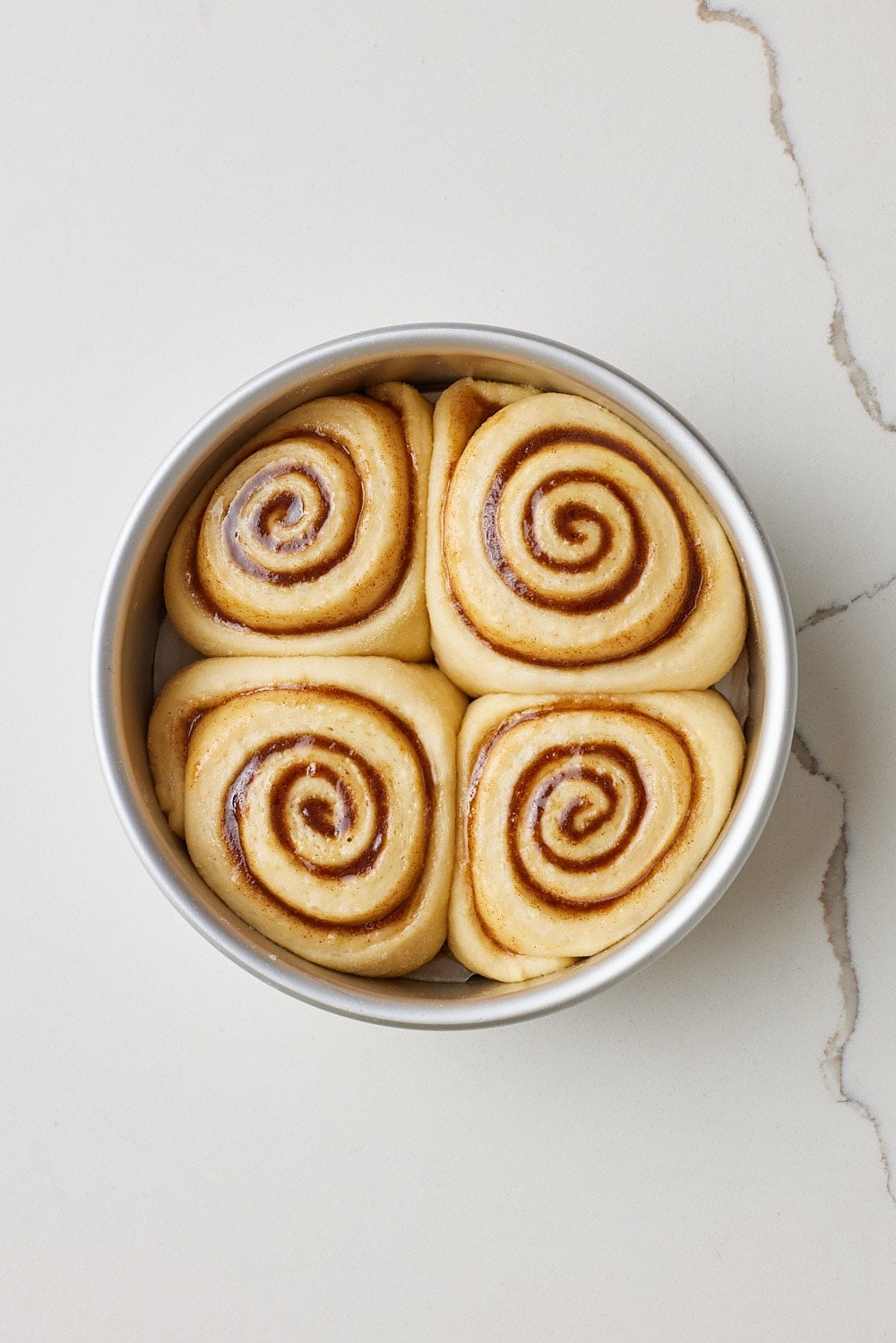 Small Batch Cinnamon Rolls12 Four small batch cinnamon rolls proofed doubled in size in the cake tin.